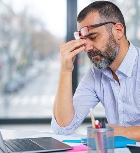 Síndico cansado, com a mão no rosto, diante do notebook