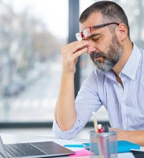 Síndico cansado, com a mão no rosto, diante do notebook